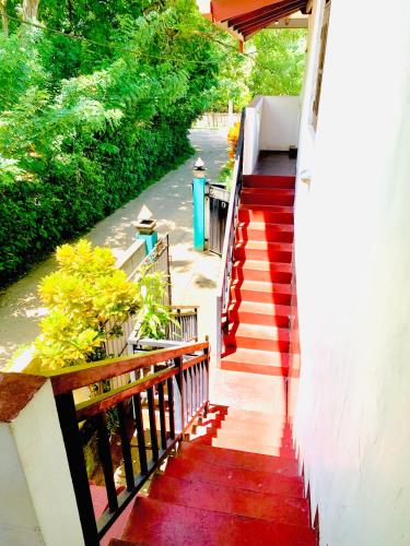 a staircase leading up to a house with a red floor at Deshan Homestay & Restaurant in Tangalle