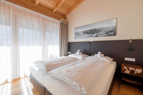 a bedroom with a large bed with white sheets at Wildkogel Resorts - DAS Bramberg in Bramberg am Wildkogel