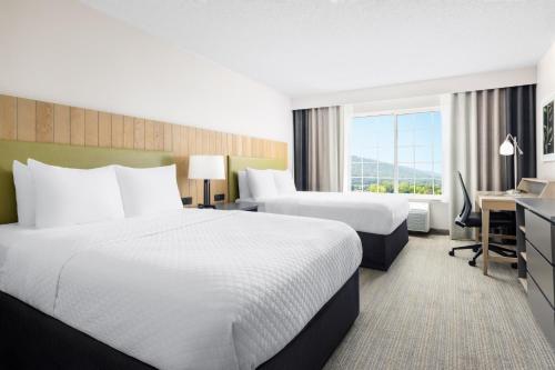 a hotel room with two beds and a desk at Country Inn & Suites by Radisson, Big Flats (Elmira), NY in Horseheads