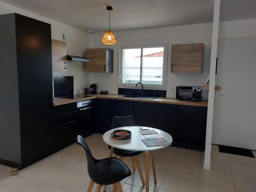 - une cuisine avec une table, des chaises et une table blanche dans l'établissement Maison neuve à Bessens, à Bessens