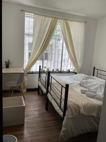 a bedroom with a bed and a desk and a window at Habitaciones en El Encanto Host in Bogotá