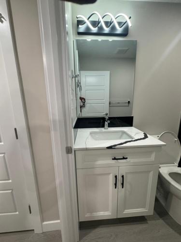 ein weißes Badezimmer mit Waschbecken und Toilette in der Unterkunft Cozy 1 bedroom basement apartment in Airdrie