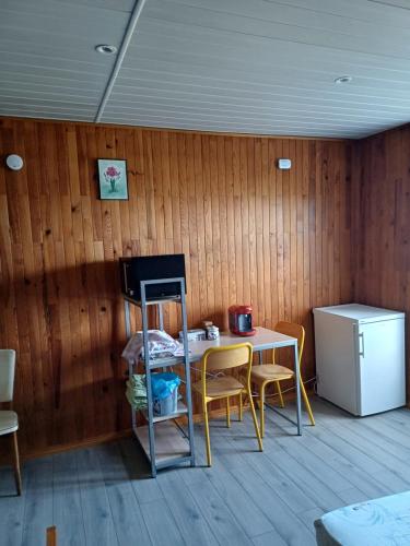 a room with a table and chairs and a refrigerator at Le Pouyet in Saint-Lattier