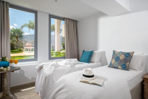a white room with a bed with a hat and a book at Parthenis Beach, Suites by the Sea in Malia