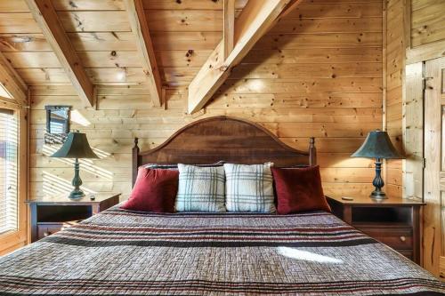 a bed in a room with wooden walls and two lamps at Groot's Place - 5 min to main parkway!! in Pigeon Forge