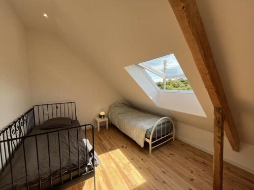 une chambre mansardée avec un lit et une fenêtre dans l'établissement Ty Sunset Portsall, à Ploudalmézeau