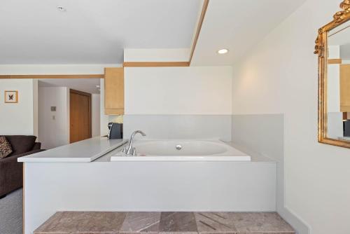 a white kitchen with a sink and a mirror at Le Chamois by Whistler Premier in Whistler
