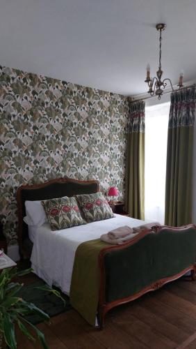 - une chambre avec un lit et du papier peint floral dans l'établissement B&B Maison de Ville Lubersac, à Lubersac