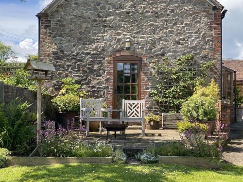 a stone house with a table and chairs in the yard at Gooseyard at Middle Farm and Cottages in Picklescott