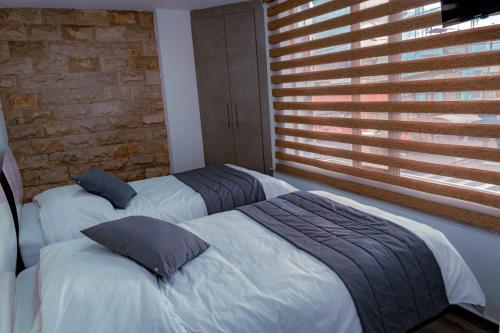 two beds in a bedroom with a brick wall at Park Hotel in Tulcán