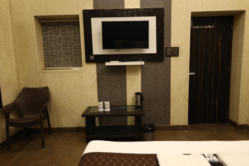 a hotel room with a tv on the wall and a table at Hotel Pardesi,Har ki pauri Road Haridwar in Haridwār