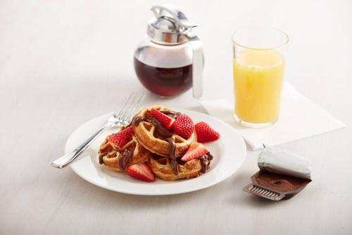 a plate of waffles with strawberries and a glass of orange juice at Residence Inn by Marriott Phoenix Chandler/South in Chandler