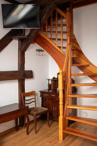 a living room with a wooden spiral staircase with a television at Folwark Pszczew in Pszczew