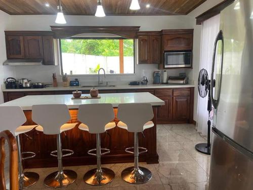 a kitchen with a island with bar stools at Casa vacacional en Playa Tambor in Puntarenas