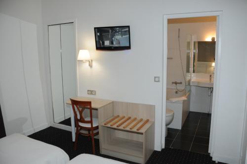 a room with a desk and a bathroom with a toilet at Hôtel Patio Brancion in Malakoff