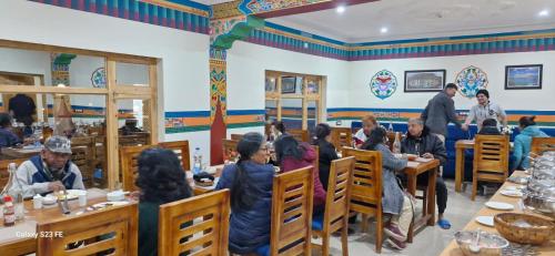 a group of people sitting at tables in a restaurant at The Nangsay Hotel in Leh