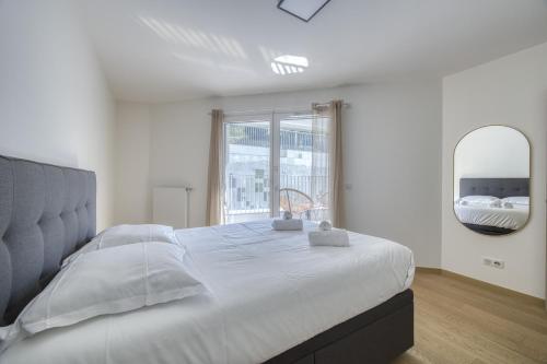 une chambre blanche avec un grand lit et un miroir dans l'établissement View point Garden, à Annecy