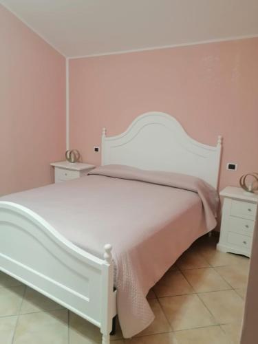 a white bed in a bedroom with pink walls at Al Carpine in Roccadaspide