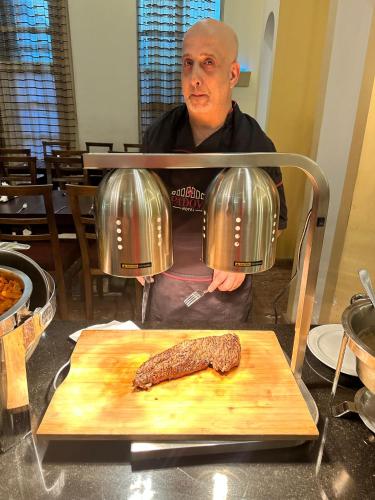 a man is standing next to a piece of meat at Le Crillon in Broummana