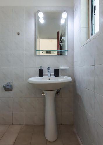 a bathroom with a white sink and a mirror at Economisa Apartments in Ialyssos