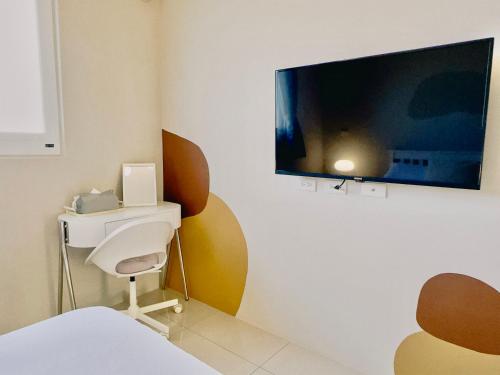 a room with a tv on a wall with a chair at Ri Yue Homestay in Taitung City