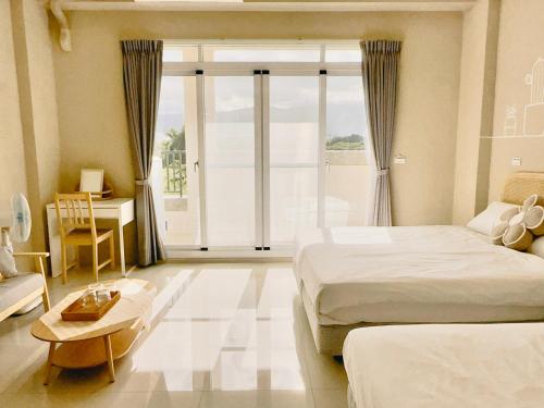 a bedroom with two beds and a desk and a window at Ri Yue Homestay in Taitung City