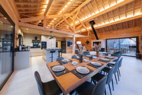 une salle à manger avec une grande table et des chaises en bois dans l'établissement Chalet luxe & spa, BLACK PEARL, à Briançon
