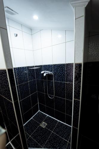 a bathroom with a shower with black and white tiles at Hotel Duet in Maydan