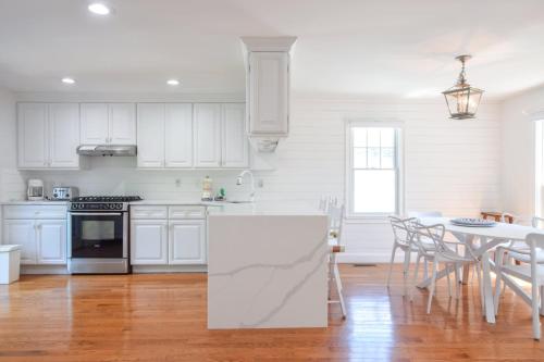 a kitchen with white cabinets and a table with chairs at Walk 0 3 Mile to Bank Street Beach in Harwich