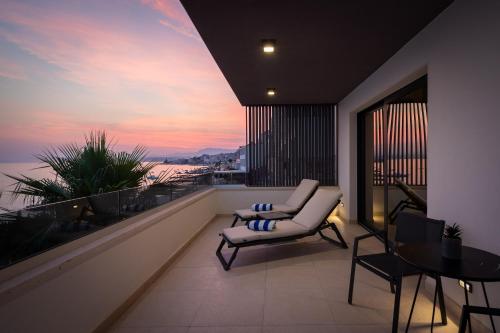 a balcony with a couch and a table and a sunset at Paoma Luxury Beach Suite with jacuzzi in Podstrana