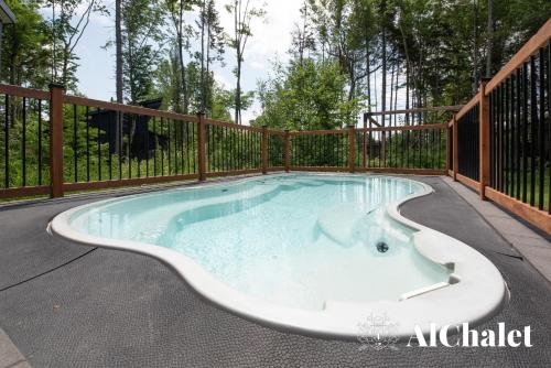 a hot tub in a deck with a fence at Sunset - Cosy boisé - Spa in Pont-Rouge