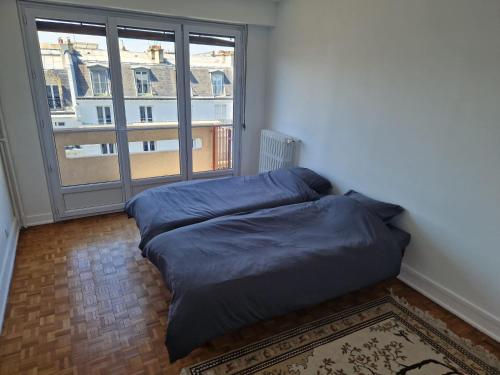 une chambre avec un lit et une grande fenêtre dans l'établissement Grand Appartement Parisien Lumineux Nation 3 chambres Etage élevé, à Paris