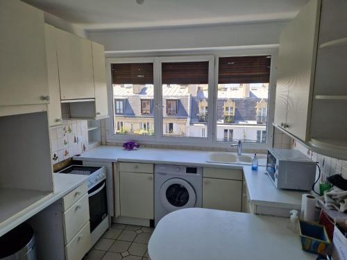 une cuisine avec un évier et une machine à laver dans l'établissement Grand Appartement Parisien Lumineux Nation 3 chambres Etage élevé, à Paris