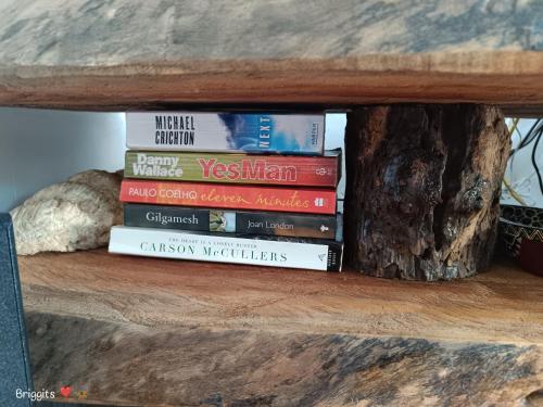 a pile of books sitting on a wooden table at Hellenas Gem in Ukunda