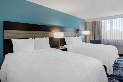 two beds in a hotel room with blue walls at Best Western Rutgers University Hotel in East Brunswick