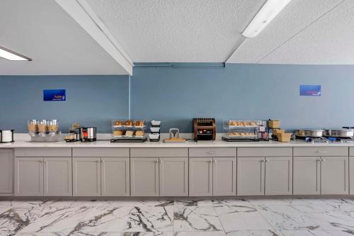 a kitchen with white cabinets and blue walls at Best Western Rutgers University Hotel in East Brunswick