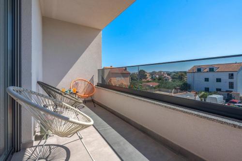 einen Balkon mit einem Stuhl und Stadtblick in der Unterkunft Brodarica Exquisite Apartments in Brodarica