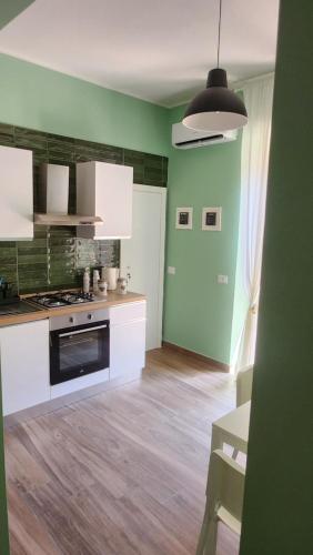 a kitchen with green walls and white cabinets at Casa Fraeli in Pozzuoli