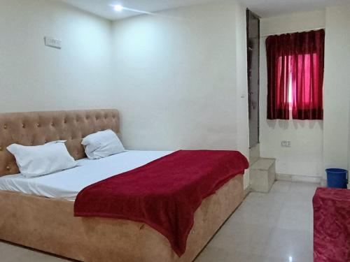 a bedroom with a bed with a red blanket on it at Metro Regency - Near Hazratganj & Charbagh in Lucknow