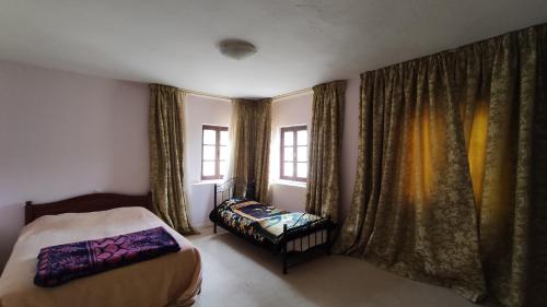 a bedroom with a bed and a chair and windows at Kasbah ADRAR in Imilchil