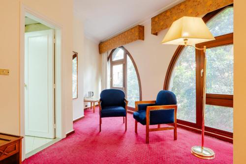 a room with two chairs and a lamp and windows at Om Kolthoom Hotel in Cairo