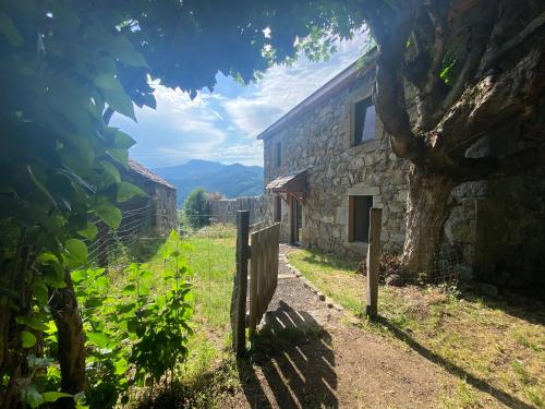 a stone house with a fence and a tree at Gîte de charme en plein cœur de l’Ardèche verte in La Rochette