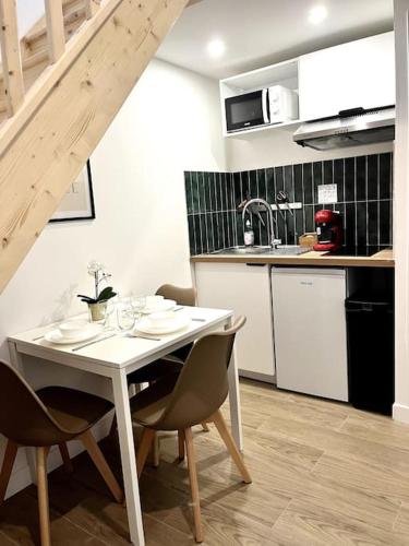 - une cuisine avec une table et des chaises blanches dans la chambre dans l'établissement 733 Nouveau studio en mezzanine proche du métro L9, à Bagnolet