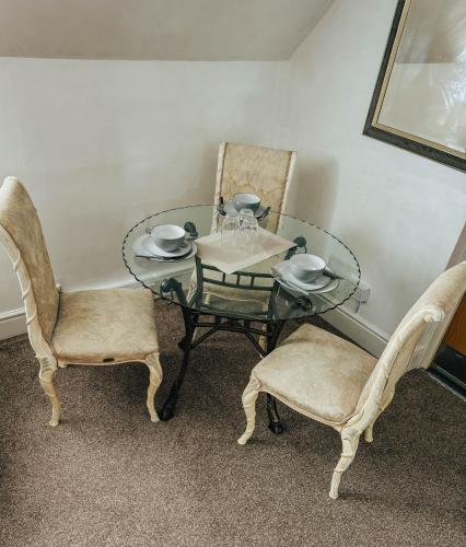 a glass table with two chairs and a table with glasses on it at Stylish Modern 1-Bed Apartment in Prime Solihull Town Centre in Solihull