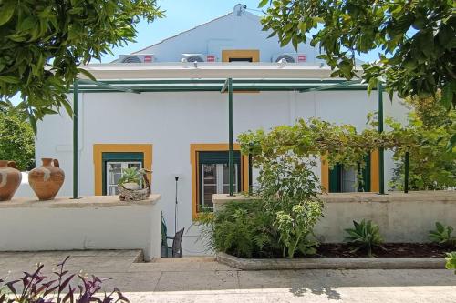 a white house with yellow and green accents at Casa 2 Jardins in Olaia