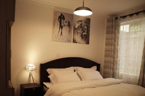 une chambre avec un lit avec des draps blancs et une fenêtre dans l'établissement Summit View Suite - A two bedroom Apartment, à Nanyuki