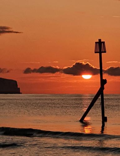 a person standing on the beach at sunset at Tranquility at Sandown Bay in Sandown