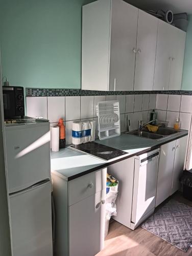 une cuisine avec des appareils électroménagers blancs et des armoires blanches dans l'établissement 12 RUE FERNAND HE93600 Aulnay SOUS BOIS, à Aulnay-sous-Bois