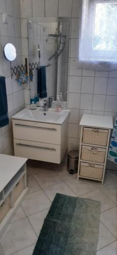 a white bathroom with a sink and a mirror at Mitra Vendégház in Balatonalmádi