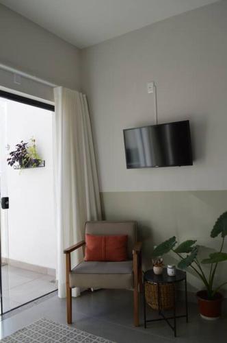 a living room with a chair and a tv on the wall at Kitnet equipada e aconchegante in Passos